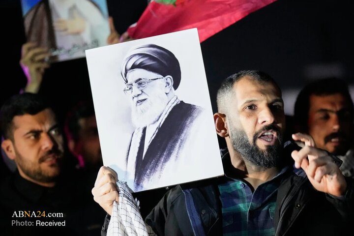معترضی با در دست داشتن تصویر آیت‌الله علی خامنه‌ای در جریان یک تجمع علیه حملات آمریکا و اسرائیل به شهرهای مختلف ایران روی پلی منتهی به منطقه سبز و سفارت آمریکا در بغداد دیده می‌شود.